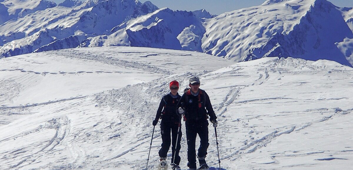 Randonneurs à raquettes dans le Beaufortain, avec panorama sur la Lauzière à l'arrière plan