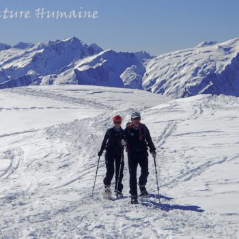 Randonneurs à raquettes dans le Beaufortain, avec panorama sur la Lauzière à l'arrière plan