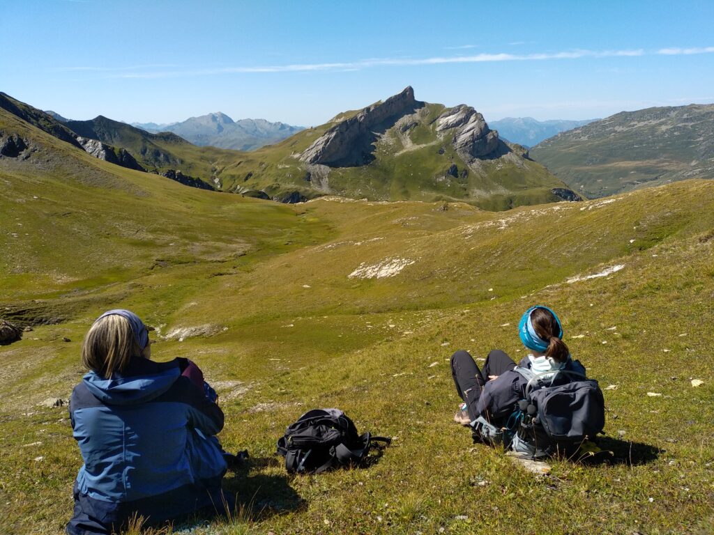 randonneurs faisant une pause dans l'herbe, et contemplant le rocher du Vent (Beaufortain)